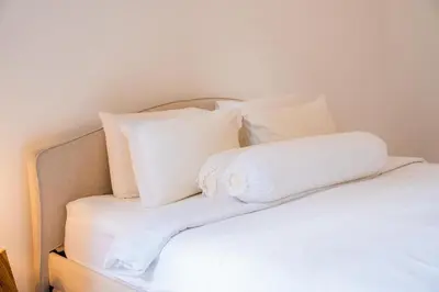 a bed with white pillows on top of it at Satori Villa Umalas in Canggu