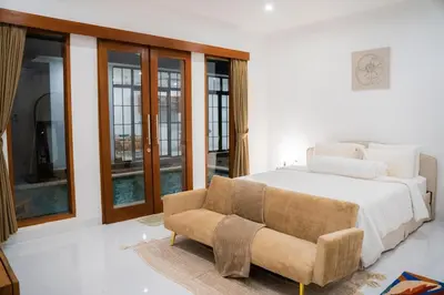 a bedroom with a bed and a couch and windows at Satori Villa Umalas in Canggu