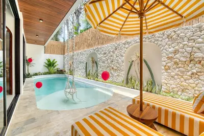 an indoor swimming pool with an umbrella and a table at Villa Tébu 3 BR Brand New Villa in Umalas in Kerobokan