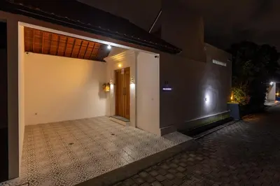 a door to a building at night with a tiled courtyard at Villa Sunshyne in Seminyak