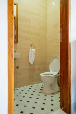a bathroom with a toilet and a tiled floor at Villa Sunshyne in Seminyak