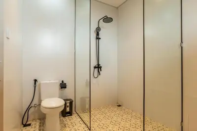 a bathroom with a toilet and a glass shower stall at Tuluscoliving villa kuta 2, 4 Bedroom & 5 Bathroom in Ngurah Rai International Airport