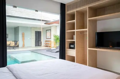 a bedroom with a television and a swimming pool at Villa Orchid Berawa in Canggu