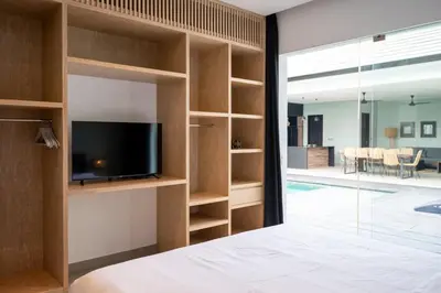 a bedroom with a tv and a room with a pool at Villa Orchid Berawa in Canggu