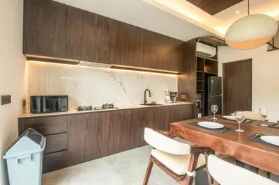 a kitchen with a wooden table and white chairs at Enchanting 5BR Canggu Villa Moments to Sea in Canggu