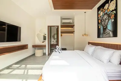 a bedroom with a large white bed and a tv at Coastal Chic 5BR Luxury Villa Canggu Beachside in Canggu