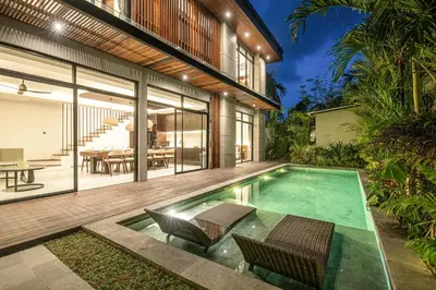 an indoor swimming pool with two chairs and a house at Coastal Chic 5BR Luxury Villa Canggu Beachside in Canggu