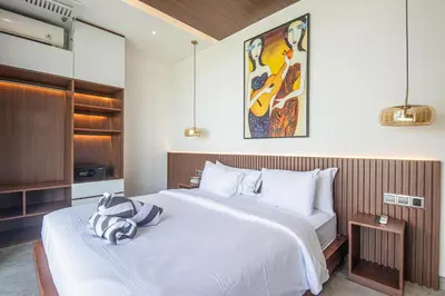 a bedroom with a large white bed and a painting on the wall at Hidden Paradise 5BR Canggu Gem Near Waves in Canggu