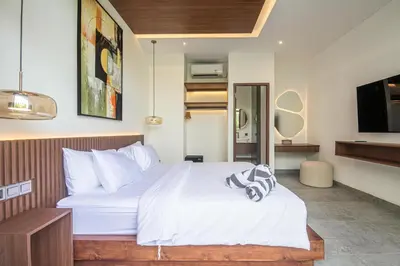 a bedroom with a white bed and a tv at Hidden Paradise 5BR Canggu Gem Near Waves in Canggu
