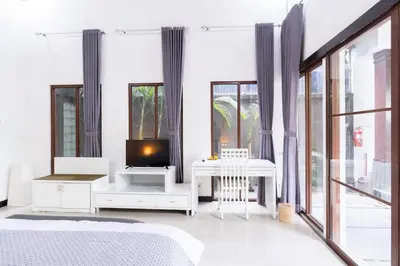 a bedroom with a bed and a tv and windows at Karen's Tropical Villa in Seminyak