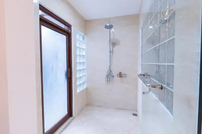 a bathroom with a shower and a glass door at Karen's Tropical Villa in Seminyak