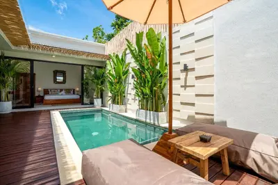 a swimming pool with a table and an umbrella at Cozy 2BR Villa Nara with Private Pool and Fitness Corner in Seminyak -Bali in Seminyak