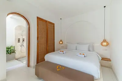 a bedroom with a large white bed and a bathroom at Villa MAVI Seminyak in Seminyak