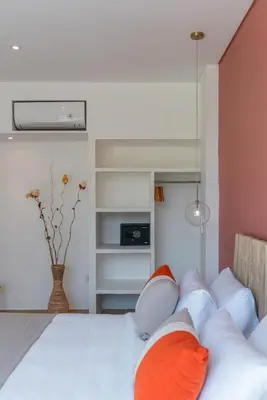 a bedroom with a bed with orange and white pillows at Wave - 6BR Luxe Canggu Villa with Rooftop & Pool in Canggu