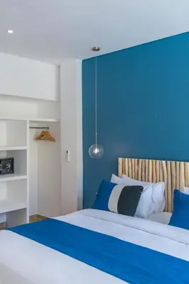 a bedroom with a bed with a blue headboard at Wave - 6BR Luxe Canggu Villa with Rooftop & Pool in Canggu