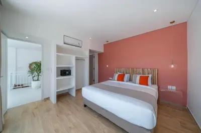 a bedroom with a large bed with an orange wall at Wave - 6BR Luxe Canggu Villa with Rooftop & Pool in Canggu