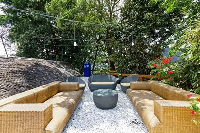 a patio with a couch and chairs and trees at Kalyca Seminyak 4 Bedroom in Seminyak