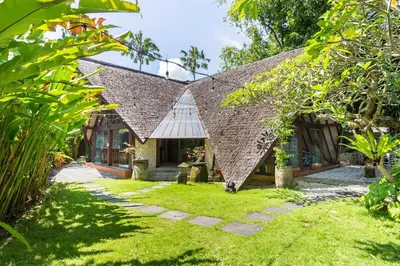 a house with a large roof with a grass yard at Kalyca Seminyak 4 Bedroom in Seminyak