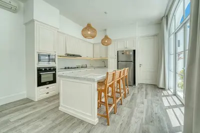 a kitchen with white cabinets and a island with chairs at Colonial Style 3BR Walking Distance to the Beach in Canggu
