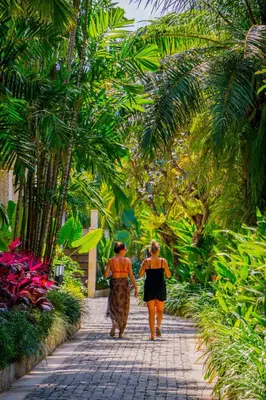 two women walking down a path in a garden at Montigo Resorts Seminyak in Seminyak