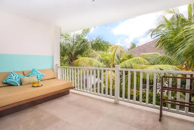 a balcony with a bench and palm trees at Montigo Resorts Seminyak in Seminyak