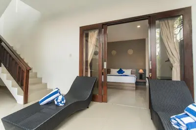 a room with a bed and two chairs and a staircase at Taman Bali Villa Kerobokan 2 in Kerobokan