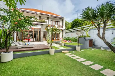 a garden with palm trees and a house at Villa Avaluna by JB Villas in Seminyak