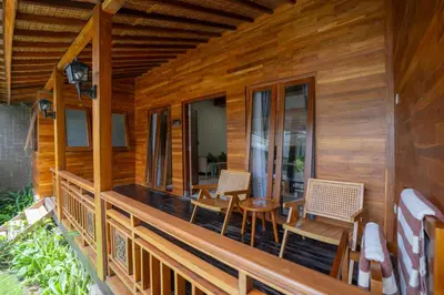 a porch of a wooden house with chairs and a table at Kania Rooms & Suite in Seminyak