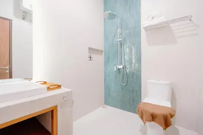 a bathroom with a shower and a toilet and a sink at Kania Rooms & Suite in Seminyak