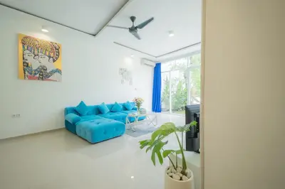 a living room with a blue couch and a ceiling fan at Casa Sopi - Art Villa 2BR Near Batu Belig Beach in Seminyak