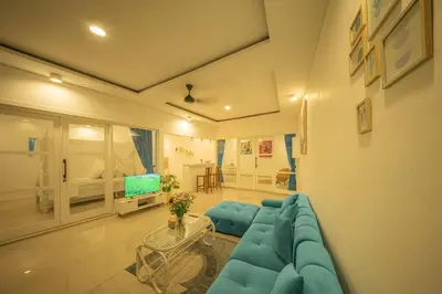 a living room with a blue couch and a tv at Casa Sopi - Art Villa 2BR Near Batu Belig Beach in Seminyak