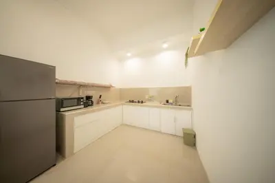 a kitchen with white cabinets and a refrigerator at Casa Sopi - Art Villa 2BR Near Batu Belig Beach in Seminyak