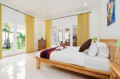 a bedroom with a large bed and large windows at Green Garden Seminyak Villa in Seminyak