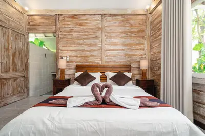 a bedroom with a large bed with wooden walls at Green Garden Seminyak Villa in Seminyak