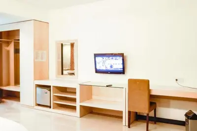 a room with a desk and a tv on a wall at First Home Stay in Ngurah Rai International Airport