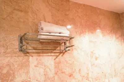 a pile of towels on a towel rack in a bathroom at First Home Stay in Ngurah Rai International Airport