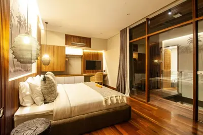 a bedroom with a large bed and a bathroom at Luxury 6BR villa Berawa beach in Canggu