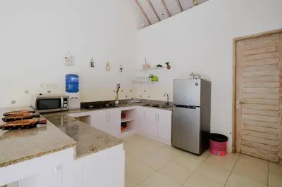 a kitchen with white cabinets and a refrigerator at Beji Ayu Seminyak - 1 Bedroom Private Villa in Seminyak