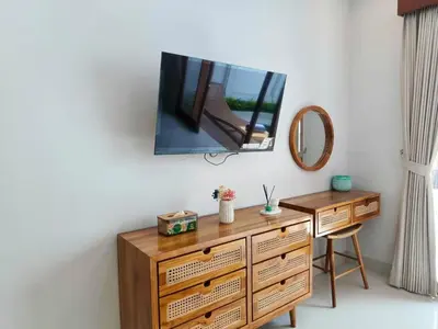 a television on a wall with a wooden dresser at RK4 Brand New 2Bedroom Villa Near Seminyak in Seminyak