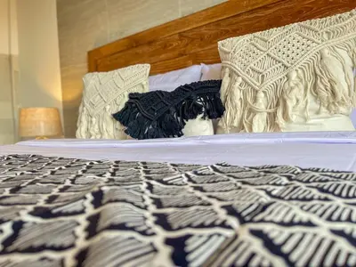 a bed with a black and white comforter and pillows at RK5, 2 beds villa 15 min walk to Double Six Beach in Seminyak