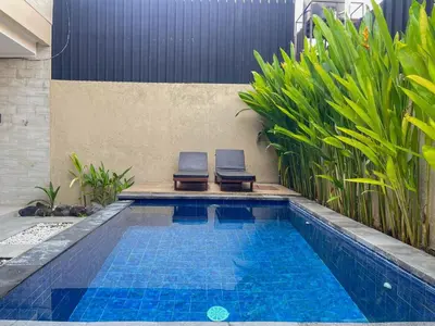 two chairs sitting next to a swimming pool at RK5, 2 beds villa 15 min walk to Double Six Beach in Seminyak