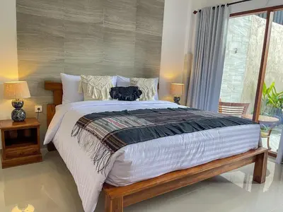 a bedroom with a large bed with two cats on it at RK5, 2 beds villa 15 min walk to Double Six Beach in Seminyak