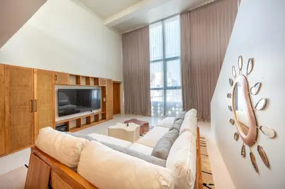 a living room with a large couch and a tv at Gate 11 Mezzanine one in Denpasar