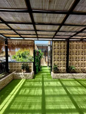 a garden with green grass and a wooden ceiling at Villa Vela 2 BR - Vela 3 with Private Pool & Rooftop in Seminyak