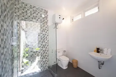 a bathroom with a shower and a toilet and a sink at Uma dharma villas 2 in Seminyak