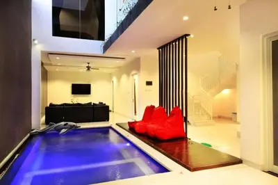 an indoor swimming pool with red pillows in a house at Villa Dreamz - six bedrooms private villa in Legian