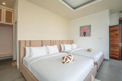 two beds in a bedroom with white walls at Splendid Villa 3Br Center Seminyak in Seminyak