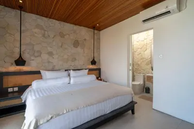 a bedroom with a large bed and a stone wall at Modern 3BR Villa Seminyak, central location in Seminyak