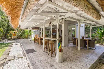 an outdoor patio with a bar and tables and chairs at Villa Sarah 4 chambres près de la plage Oberoi Seminyak in Seminyak
