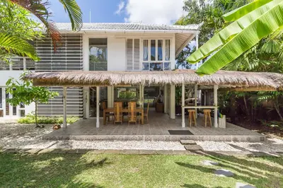 a house with a thatched porch with tables and chairs at Villa Sarah 4 chambres près de la plage Oberoi Seminyak in Seminyak